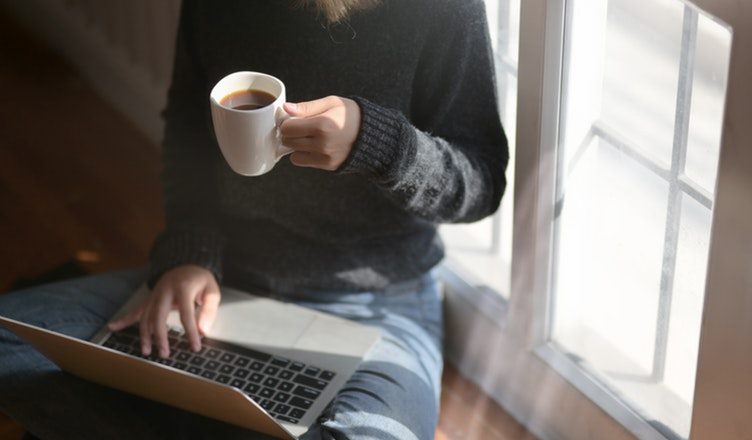 Kvinde med computer og kop kaffe